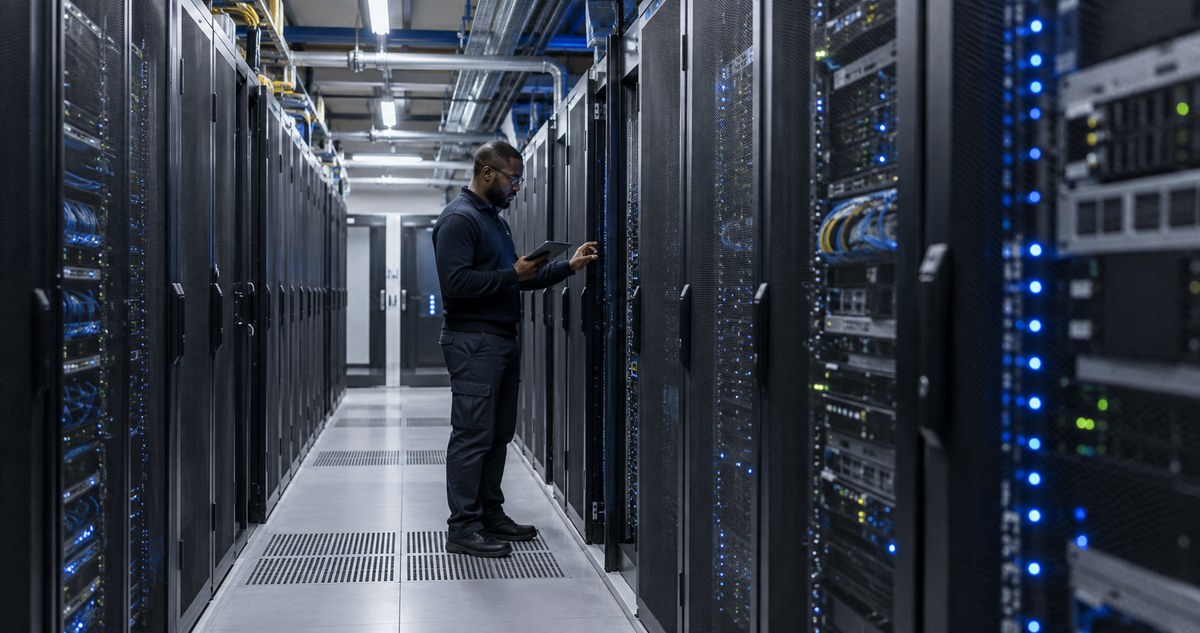 AI-generated realistic image of a fictional technician inspecting server racks and cooling infrastructure in a data-centre aisle