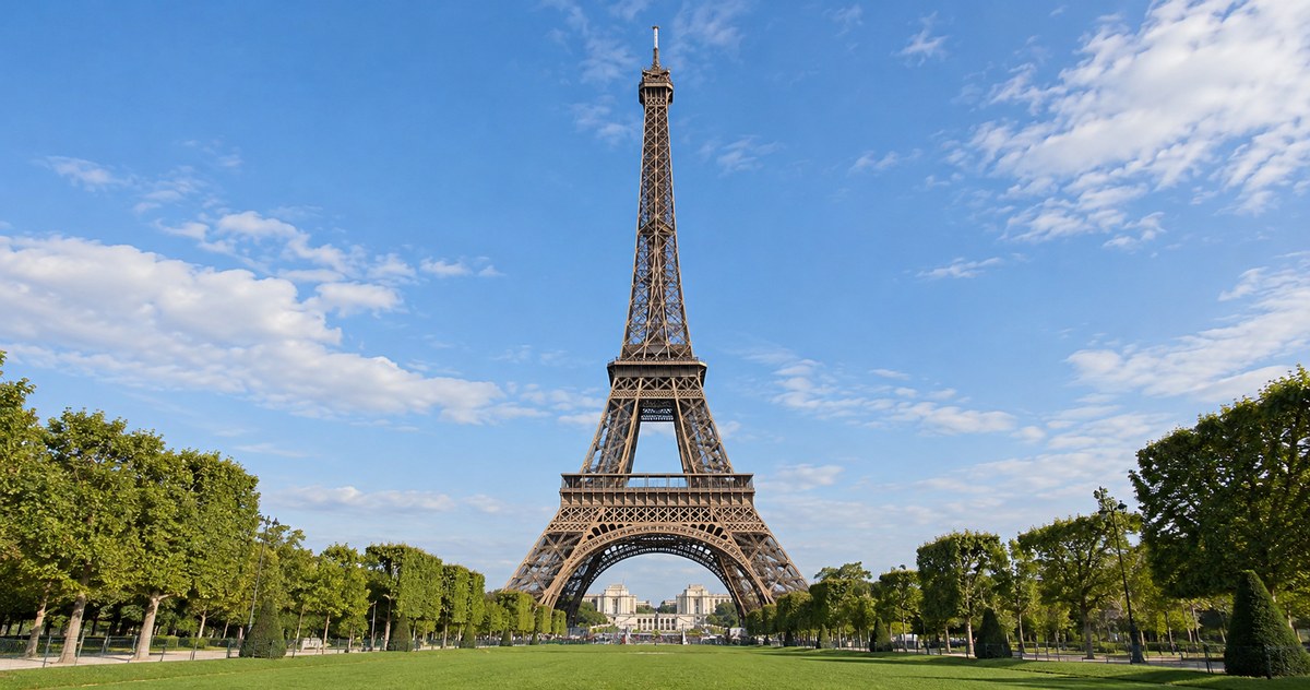 AI-generated photo-style contemporary daytime view of the complete Eiffel Tower across the Champ de Mars