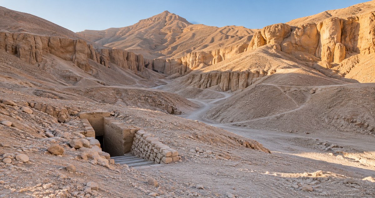 AI-generated realistic arid limestone valley with a small rock-cut tomb entrance inspired by the Valley of the Kings